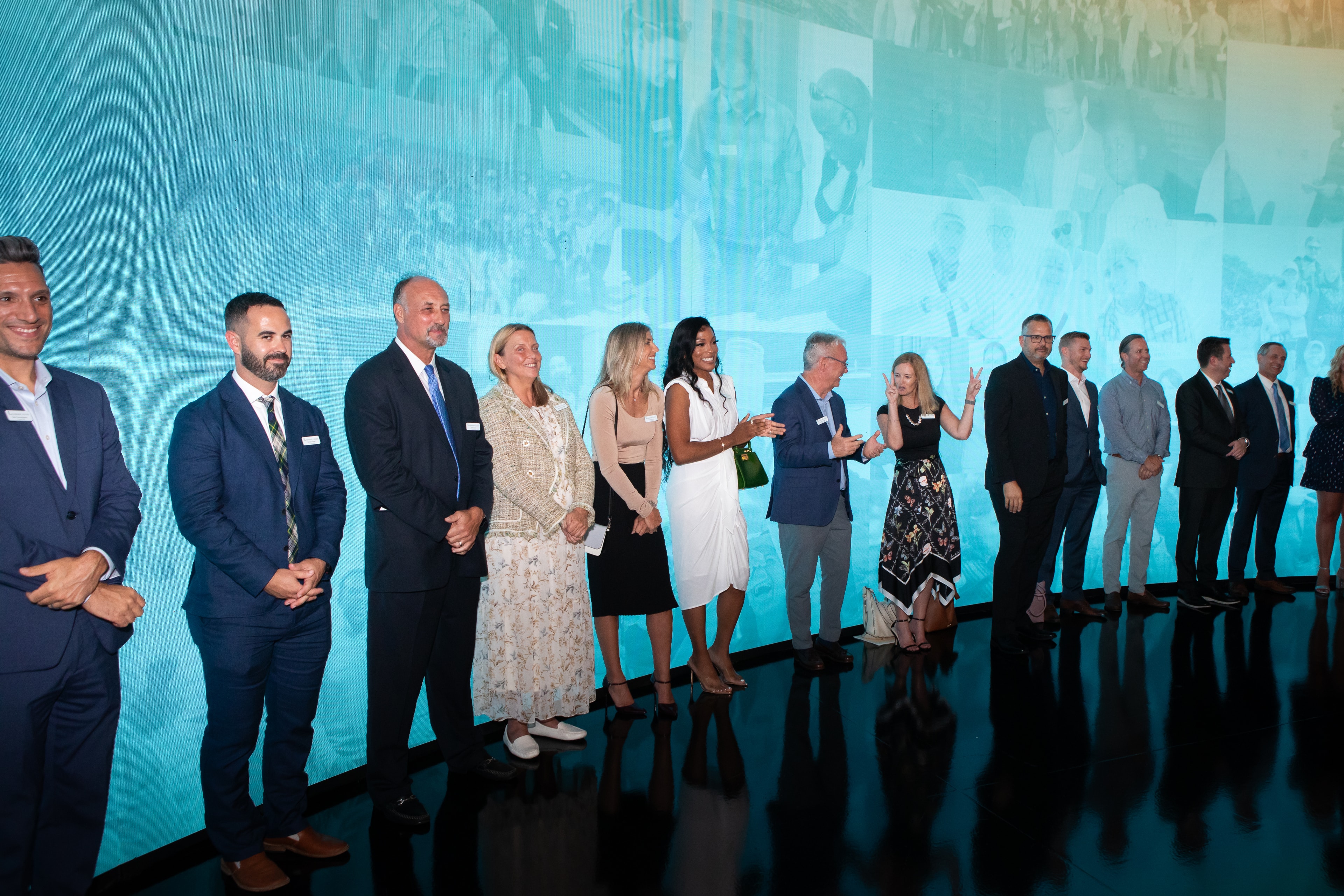 Leadership Collier honorees lined up in front of the teal LED wall
